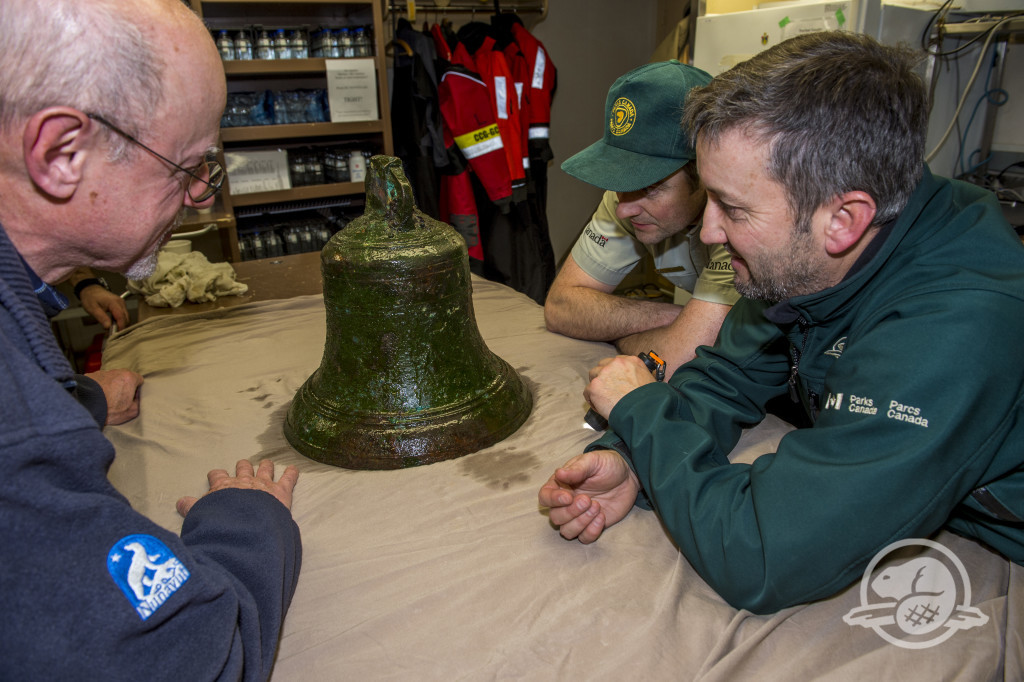 Douglas Stenton (left) Ryan Harris (middle) and Jonathan Moore examine the ship’s bell.