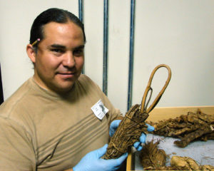 Louie Garcia examines a prehistoric loom anchor credit: American Museum Of Natural History, Cat. No. H/15724/Laurie Webster