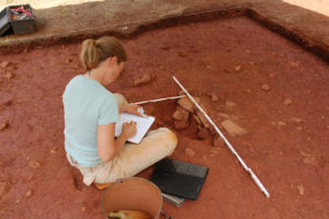 Monticello archaeologist Karen Smith records a cross section though a small borrow pit at Site 8, a late eighteenth-century domestic site that was once home to enslaved field laborers. Researchers believe this pit and others like it were dug to obtain clay for chinking the log houses and plastering their wooden chimneys that stood nearby. Credit: Thomas Jefferson Foundation.