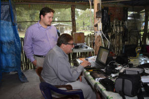 Arlen Chase (sitting) and his son Adrian work on a computer in a research laboratory at Caracol. Adrian has created a computer algorithm to help them locate small reservoirs with LiDAR. Credit: Courtesy of D.Z. Chase, Caracol Archaeological Project.